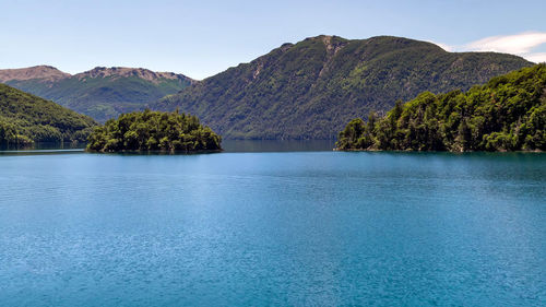 Scenic view of lake and mountains against blue sky