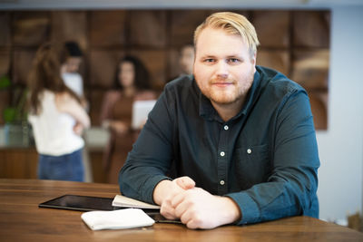 Portrait of businessman leaning on desk at office