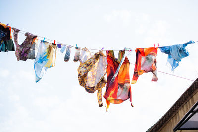 Low angle view of colorful clothes drying on clothesline against sky