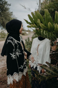 Rear view of women standing by plants on field