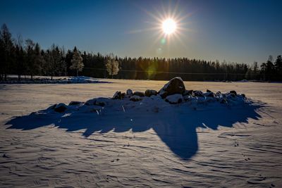 People on snow covered landscape against sky during sunset