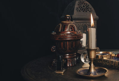 Close-up of illuminated lamp on table against black background