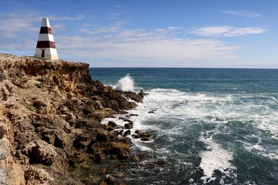 Lighthouse by sea against sky