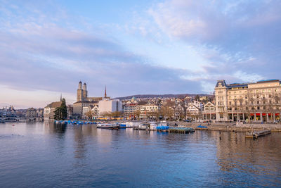 Buildings at waterfront against cloudy sky