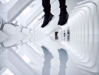 Low section of person jumping reflected on floor