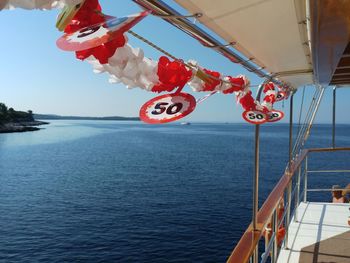 Red flag hanging on boat in sea against sky