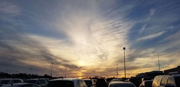 Cars on street against sky at sunset