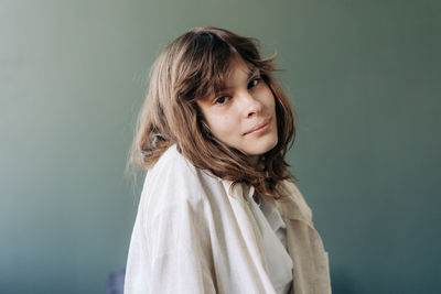Portrait of young woman standing against wall