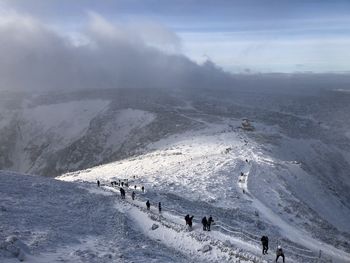 Group of people on snowcapped mountain against sky