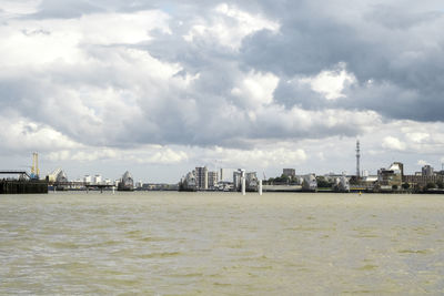 Sea by buildings in city against sky