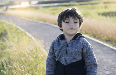 Boy with eyes closed standing on land