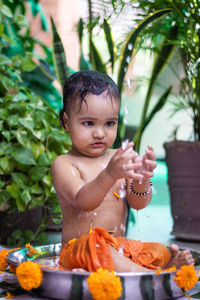 Cute toddler baby boy bathing in decorated bathtub at outdoor from unique perspective