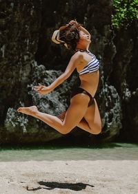 Side view of woman jumping against trees