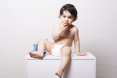 Portrait of young woman drinking water against white background