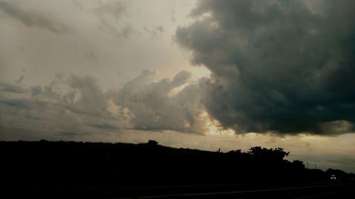 Silhouette landscape against cloudy sky