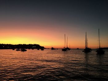 Silhouette boats in sea at sunset