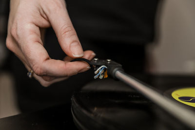 Cropped hand of woman holding record player needle