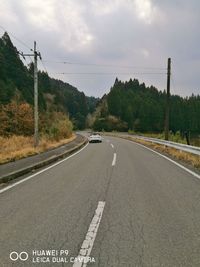 Road by trees against sky