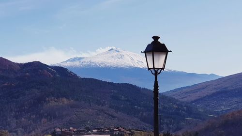 Rear view of street light and mountains against sky