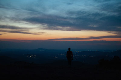 Silhouette man looking at mountain against sky during sunset
