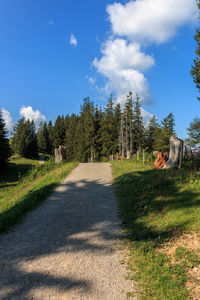 Road amidst trees on field against sky