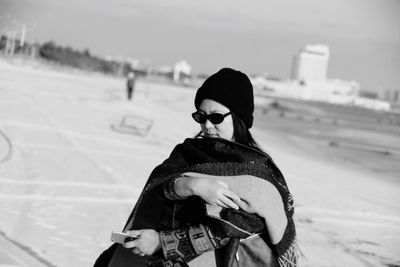 Woman wearing sunglasses while standing on street during winter