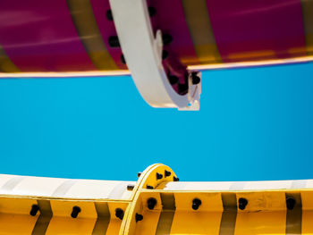 Low angle view of yellow wheel against blue sky