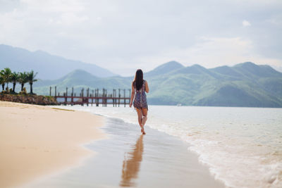 Rear view of woman walking on shore at beach