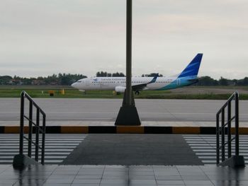 Airplane on airport runway against sky