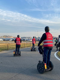 Rear view of people riding bicycle on road in city