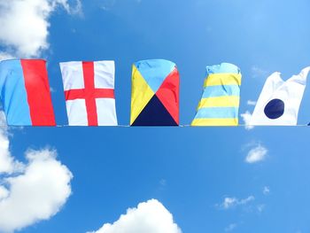 Low angle view of flags against blue sky