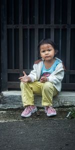 Portrait of boy sitting on footpath