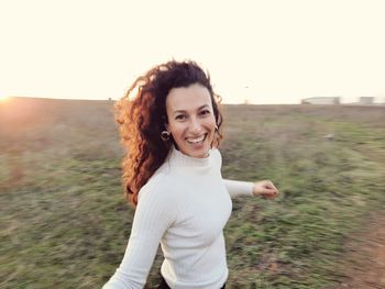 Portrait of smiling young woman standing against sky during sunset