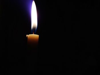 Close-up of lit candle in darkroom