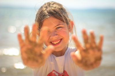 Portrait of smiling girl showing dirty hands at beach