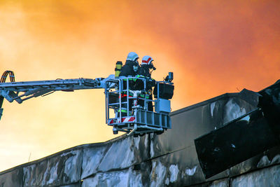 Low angle view of factory against orange sky