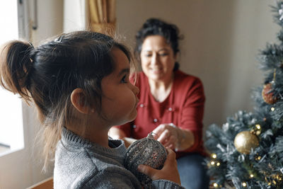 Grandparents decorate the christmas tree with their little granddaughter