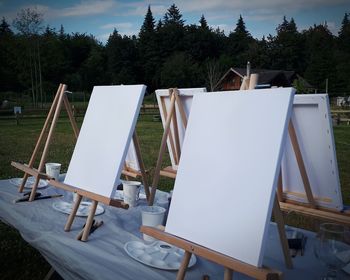 Deck chairs and tables on field against sky