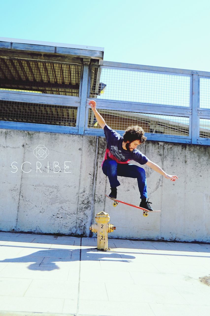 FULL LENGTH OF YOUNG WOMAN JUMPING AGAINST BUILDING