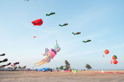 Low angle view of balloons flying over beach against sky