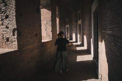 Woman standing by wall of building