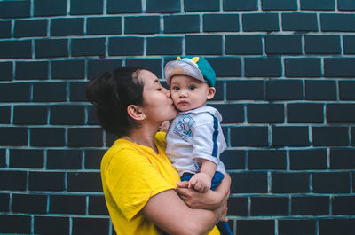 Portrait of a smiling boy against brick wall