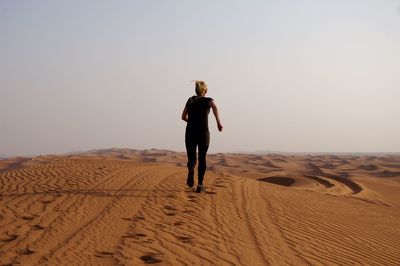 Full length of man walking on sand dune