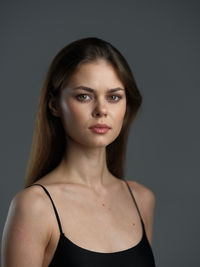 Portrait of young woman against black background