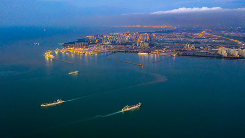 High angle view of illuminated city by sea