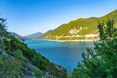 Scenic view of lake and mountains against clear blue sky