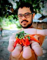 Close-up portrait of man holding red chili peppers