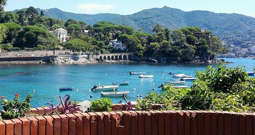 Boats moored on sea by mountains against sky