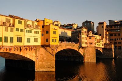 Bridge over river in city against clear sky