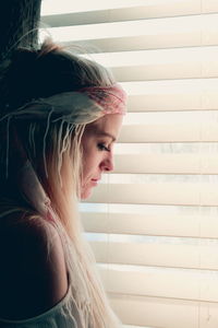 Thoughtful beautiful woman standing near window